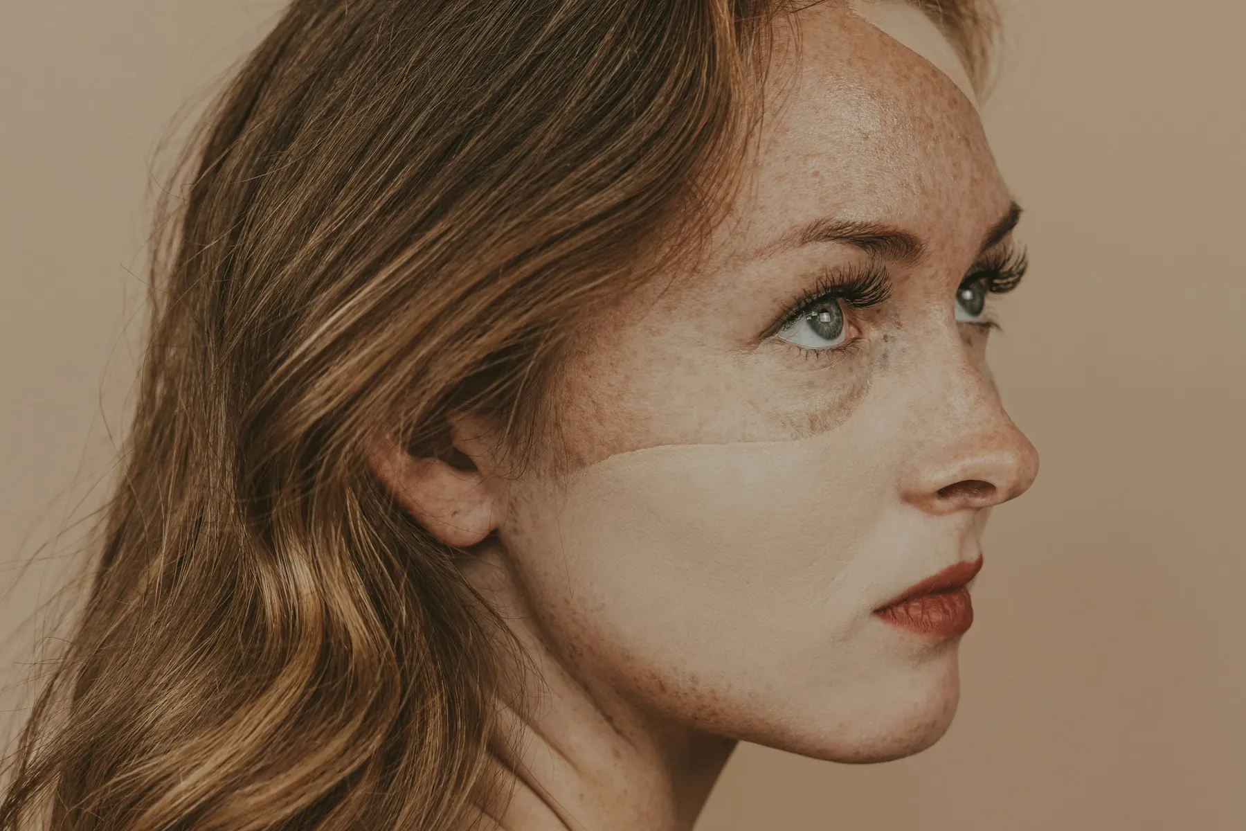 Perfil de una mujer joven con la mirada al frente sobre un fondo beige
